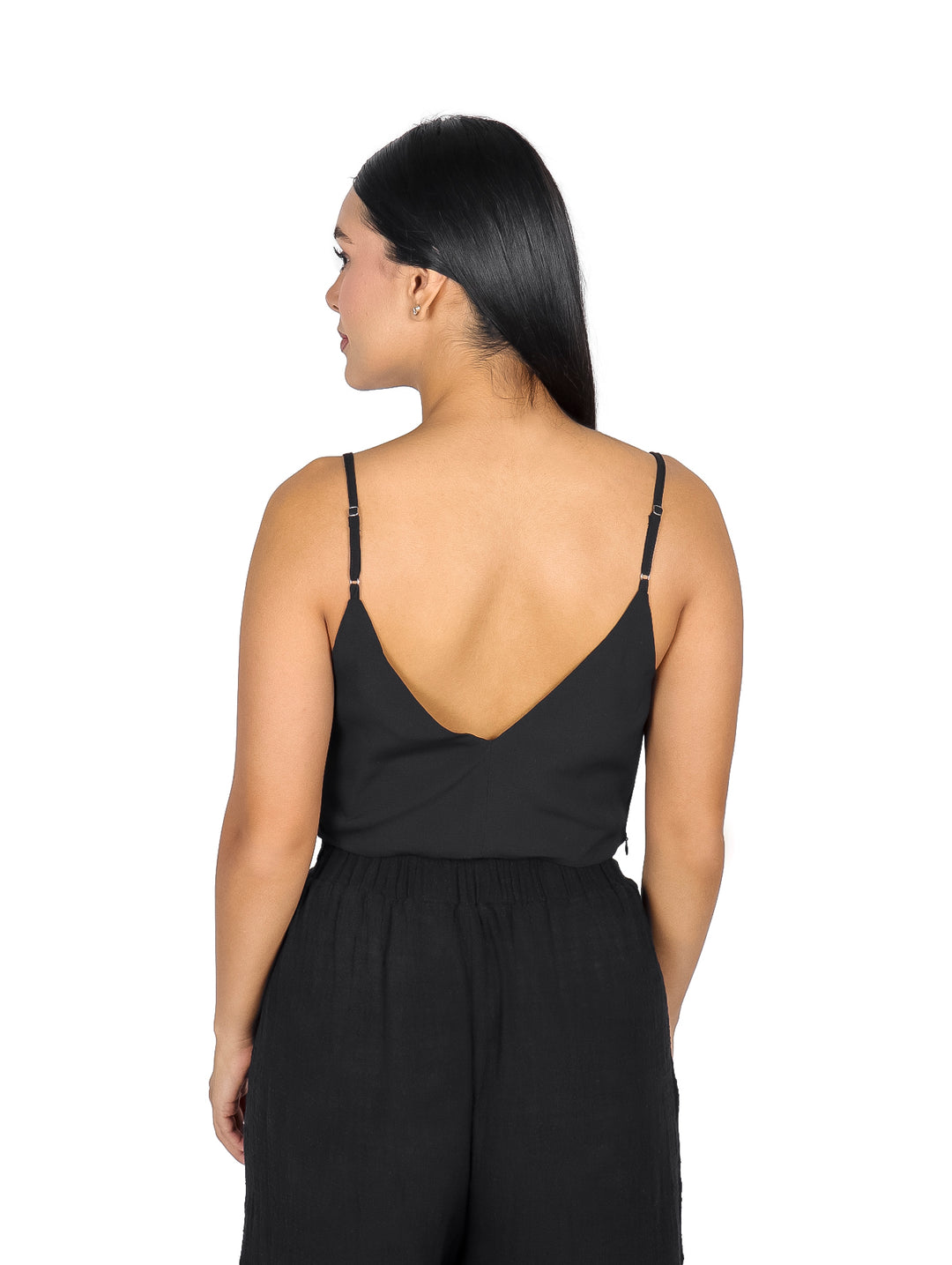 Mujer vistiendo un top negro de cuello columpio y tirantes delgados.