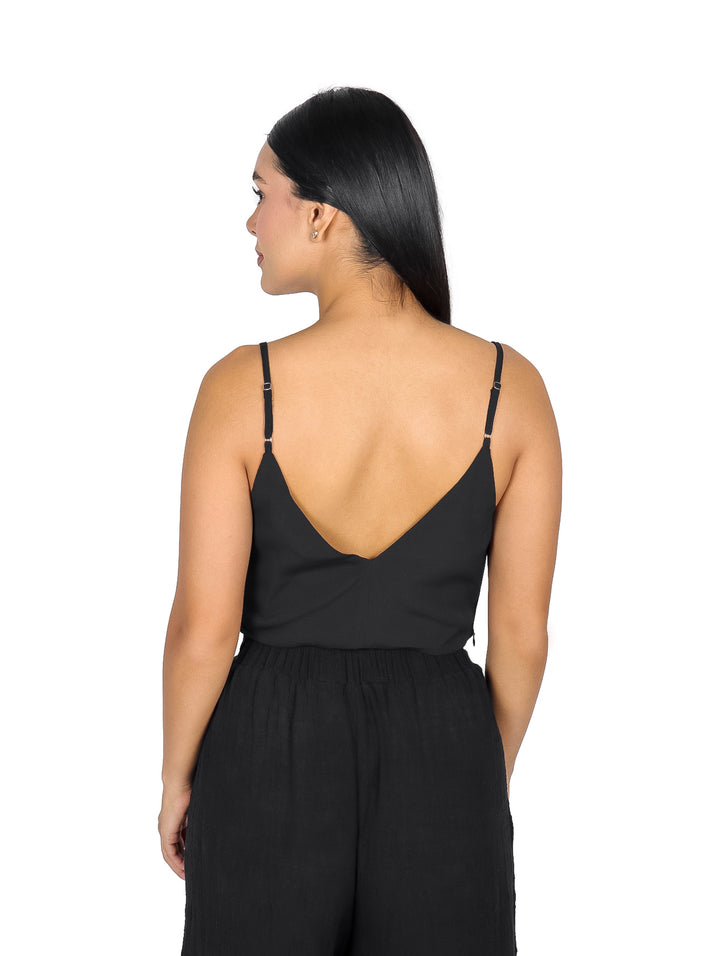 Mujer vistiendo un top negro de cuello columpio y tirantes delgados.