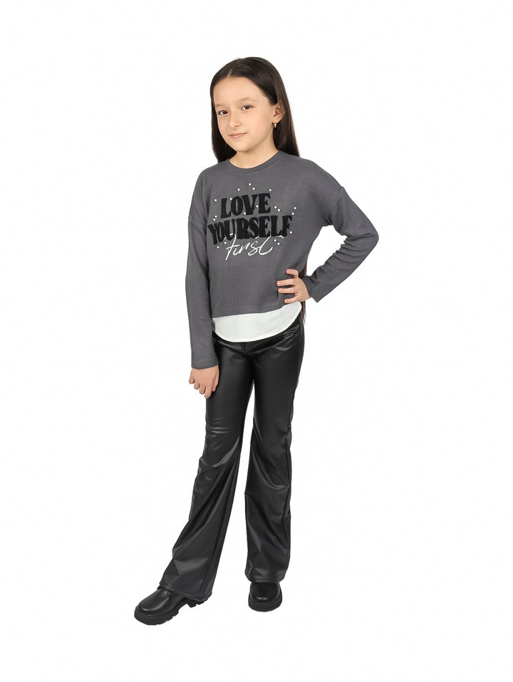 Pantalón negro de piel sintética para niño o niña con corte amplio y acabado brillante.