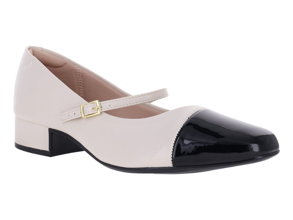 Zapato blanco de tacón bajo con punta negra brillante y correa con hebilla dorada.