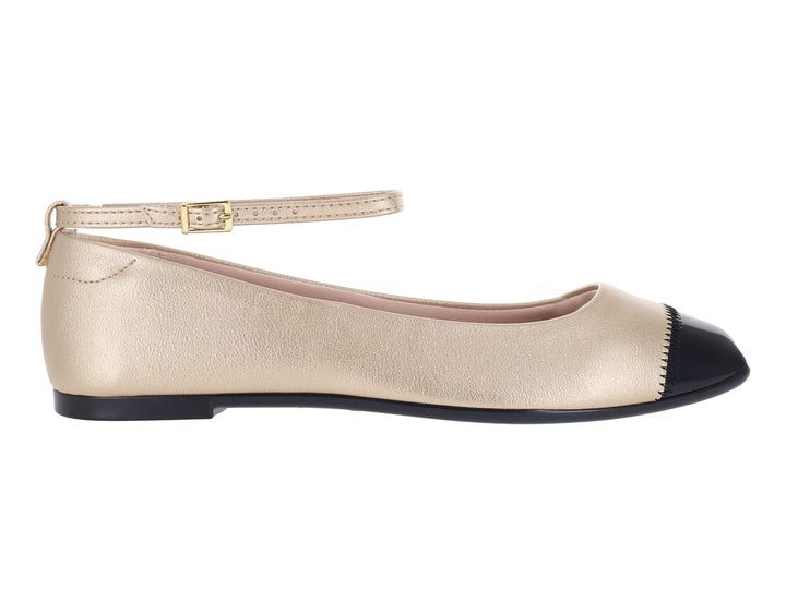 Zapato plano color dorado con punta negra y correa ajustable al tobillo.