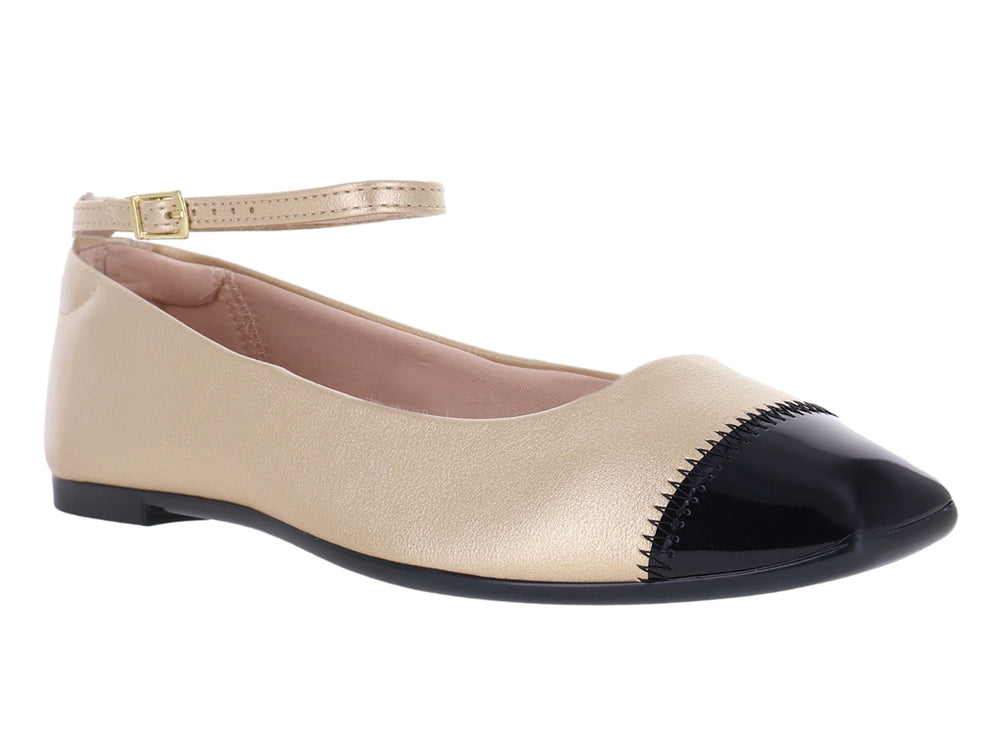 Zapato plano color dorado con punta negra y correa ajustable al tobillo.