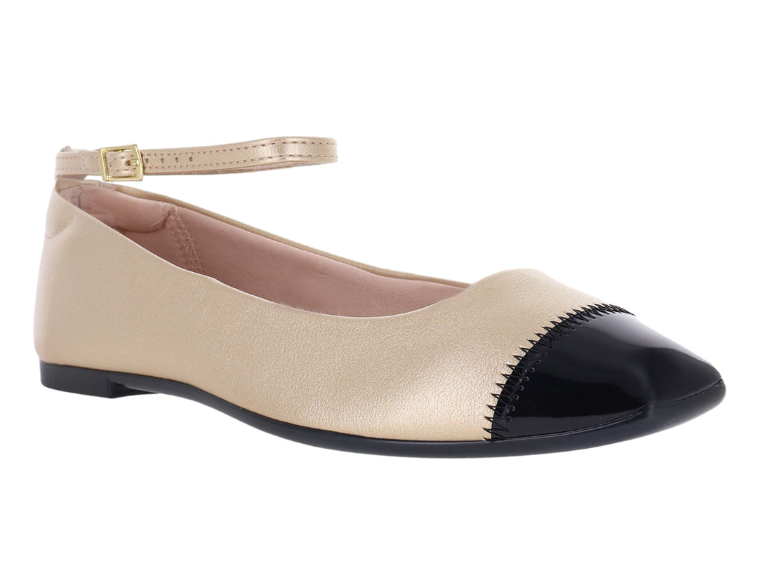 Zapato plano color dorado con punta negra y correa ajustable al tobillo.