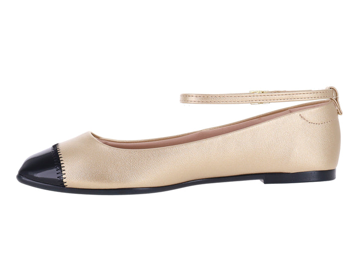 Zapato plano color dorado con punta negra y correa ajustable al tobillo.