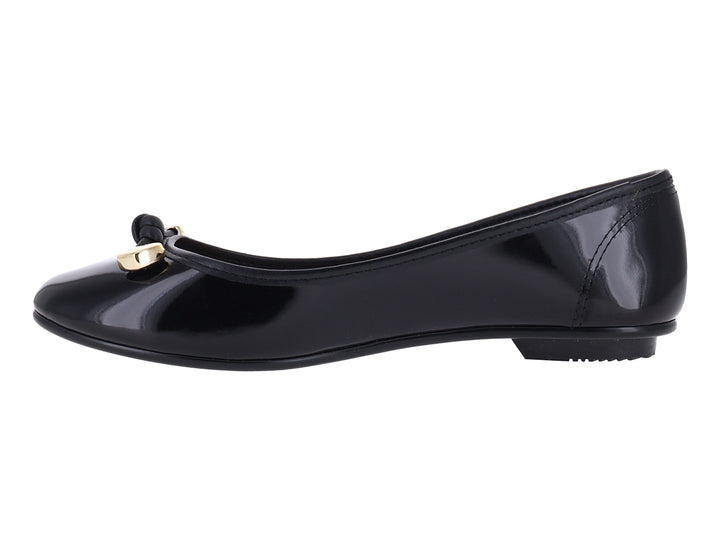 Zapato plano tipo ballerina color negro brillante con detalle decorativo dorado en la punta.
