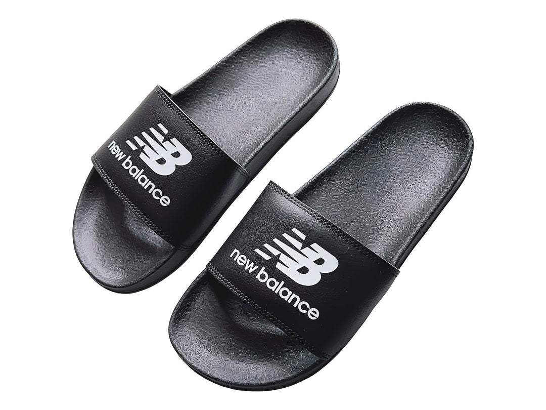 Sandalia deslizante New Balance de color negro con suela plana y correa ancha.
