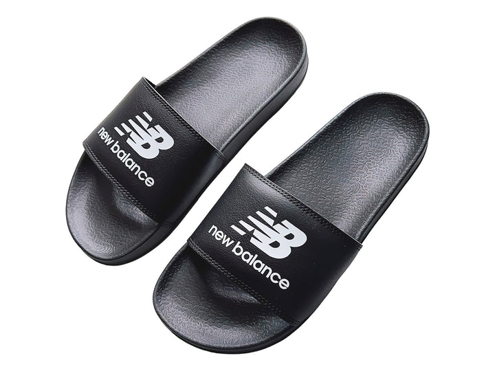 Sandalia deslizante New Balance de color negro con suela plana y correa ancha.