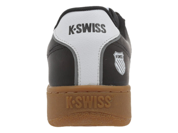 Tenis K-Swiss color negro con rayas blancas y suela de goma color marrón.