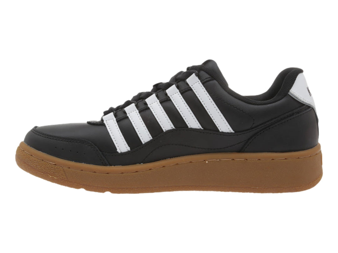 Tenis K-Swiss color negro con rayas blancas y suela de goma color marrón.