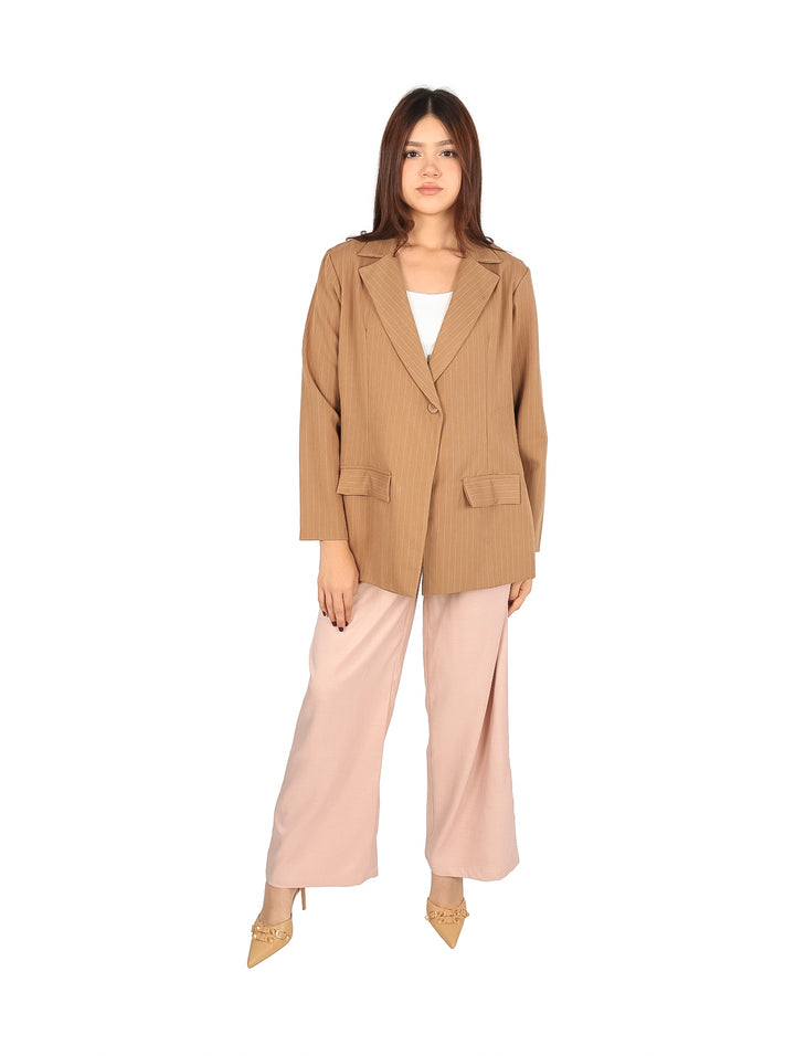 Mujer vistiendo un saco color beige con rayas verticales finas y bolsillos frontales.