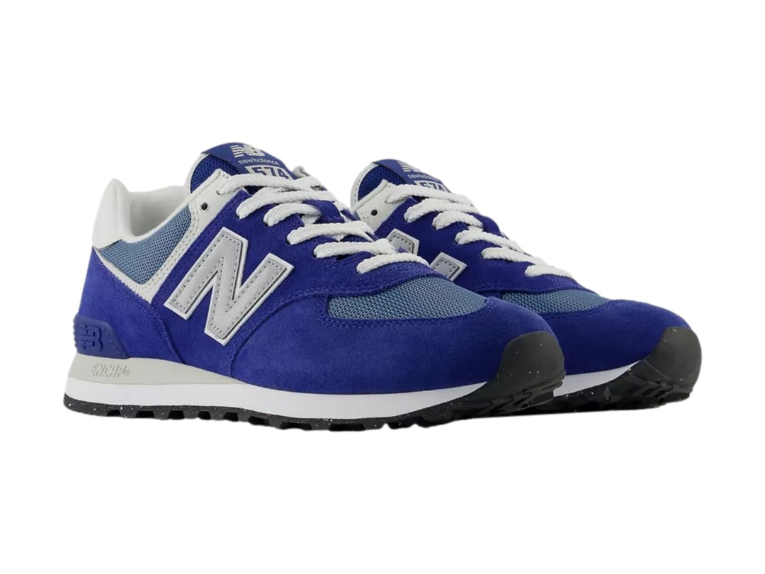 Tenis New Balance 574 color azul con detalles en gris y blanco, vista lateral sobre fondo blanco.
