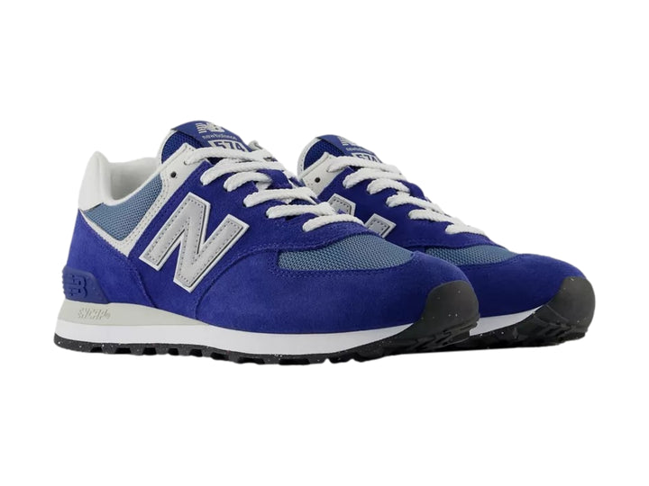 Tenis New Balance 574 color azul con detalles en gris y blanco, vista lateral sobre fondo blanco.
