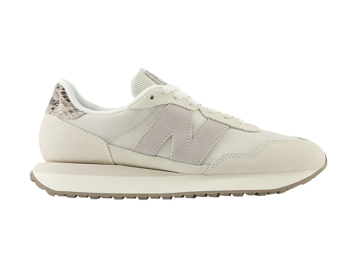 Tenis New Balance color beige con detalles en gamuza y talón con diseño de piel de serpiente.