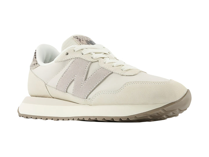 Tenis New Balance color beige con detalles en gamuza y talón con diseño de piel de serpiente.