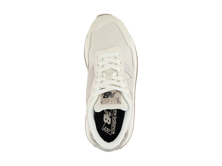 Tenis New Balance color beige con detalles en gamuza y talón con diseño de piel de serpiente.
