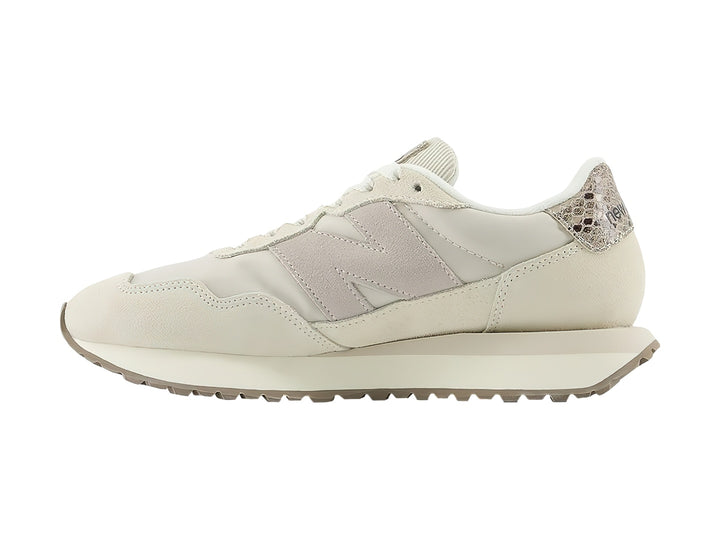 Tenis New Balance color beige con detalles en gamuza y talón con diseño de piel de serpiente.