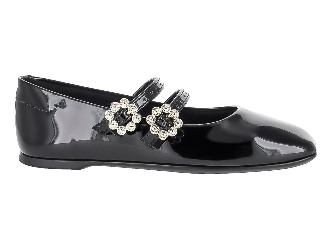 Zapato plano negro de charol para niña con dos correas decoradas con hebillas de pedrería blanca.