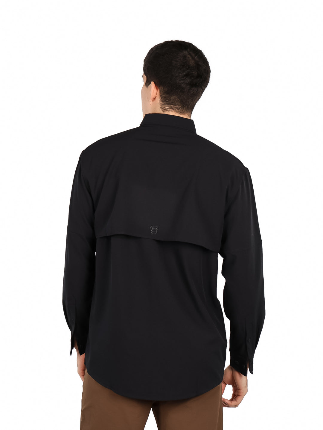 Hombre vistiendo una camisa negra de manga larga con tecnolog�a outdoor y pantalones color caf�.