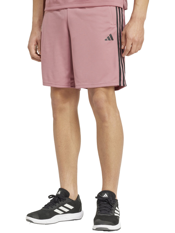 Hombre vistiendo shorts deportivos Adidas color rojo preloved crimson con tres franjas negras laterales.