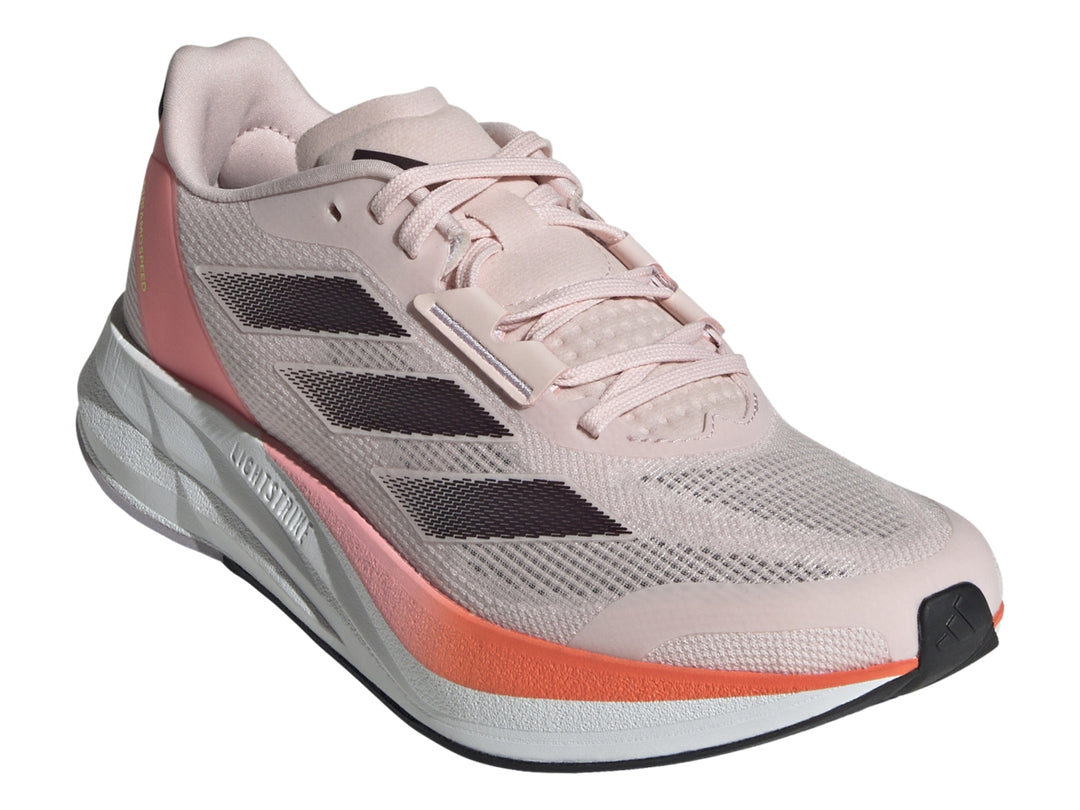 Tenis deportivos Adidas color rosa con franjas grises, detalles naranjas y suela blanca.