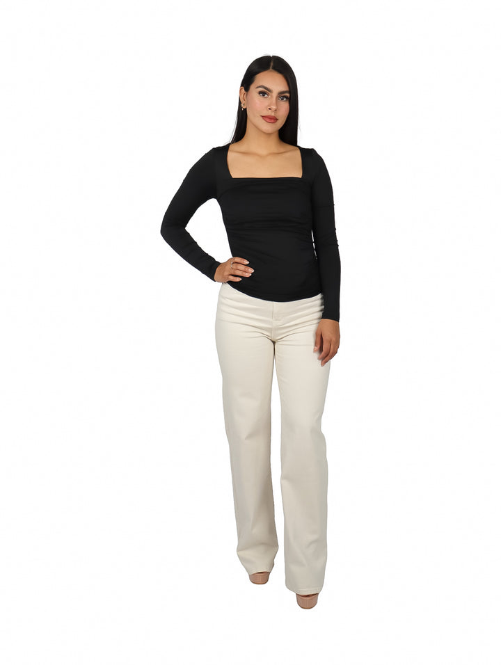 Mujer vistiendo blusa negra de manga larga con escote cuadrado y pantalones blancos.