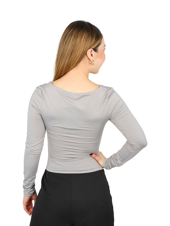 Mujer vistiendo blusa gris de manga larga con escote cuadrado y pantalones negros.