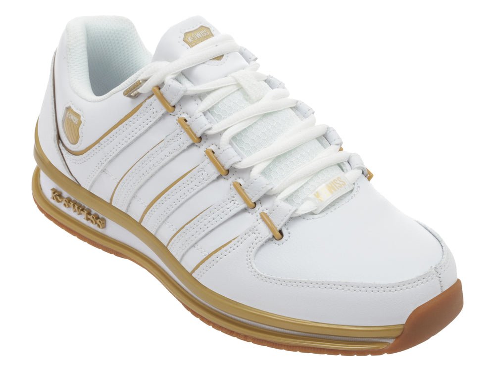 Tenis deportivos K-Swiss color blanco con detalles lineales y suela en color dorado.