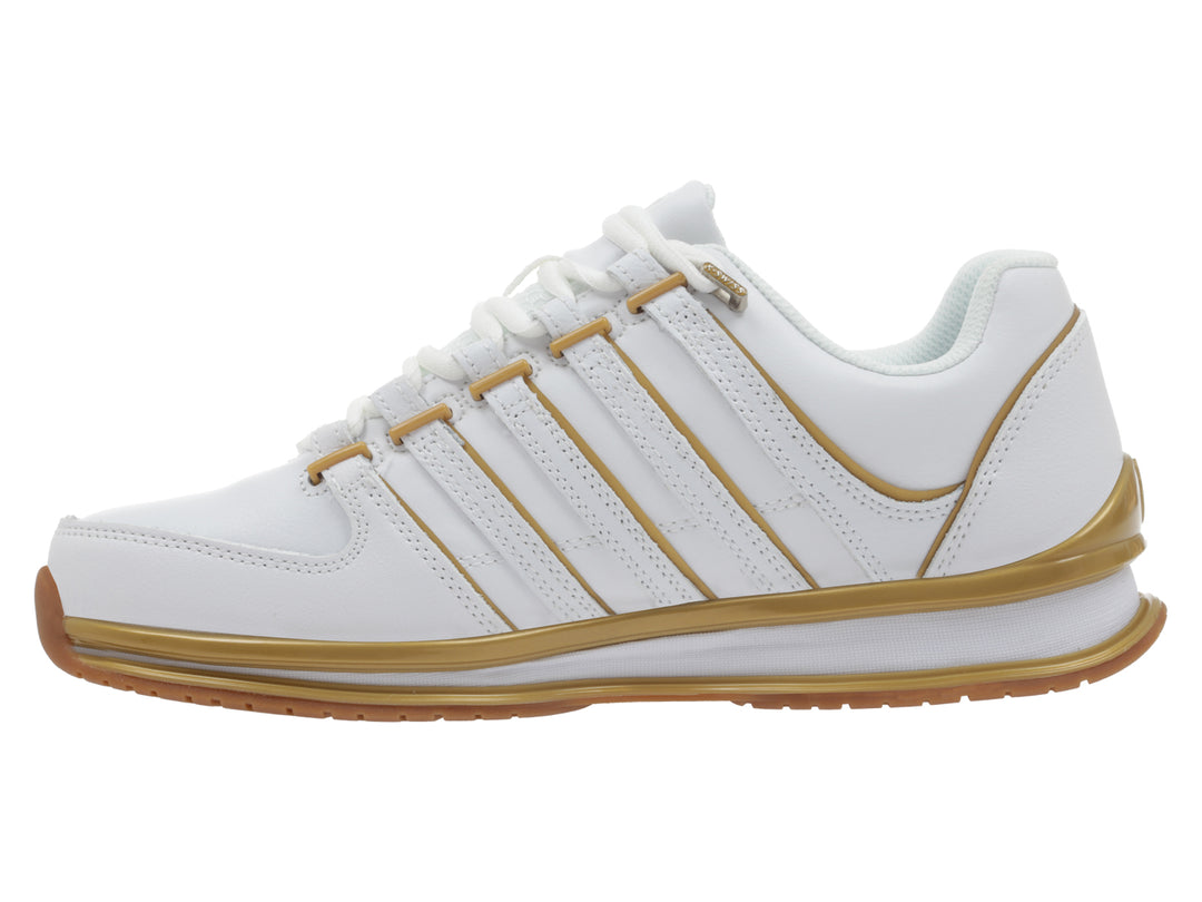 Tenis deportivos K-Swiss color blanco con detalles lineales y suela en color dorado.