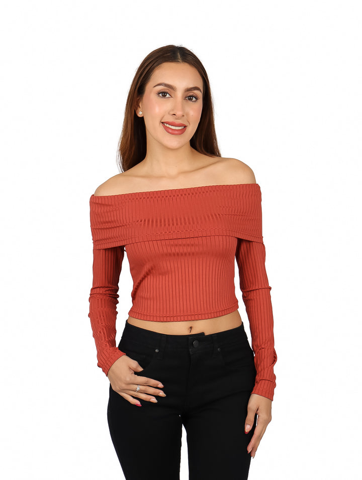 Mujer vistiendo blusa marrón de hombros descubiertos y manga larga con pantalones negros.