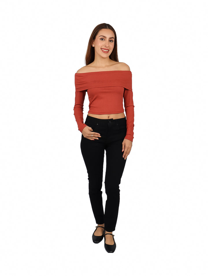 Mujer vistiendo blusa marrón de hombros descubiertos y manga larga con pantalones negros.