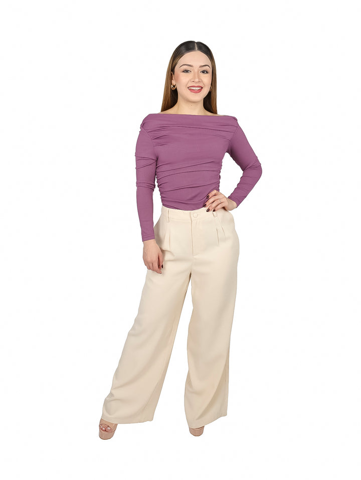 Mujer vistiendo blusa ajustada color morado de hombros descubiertos y pantalones color crema.