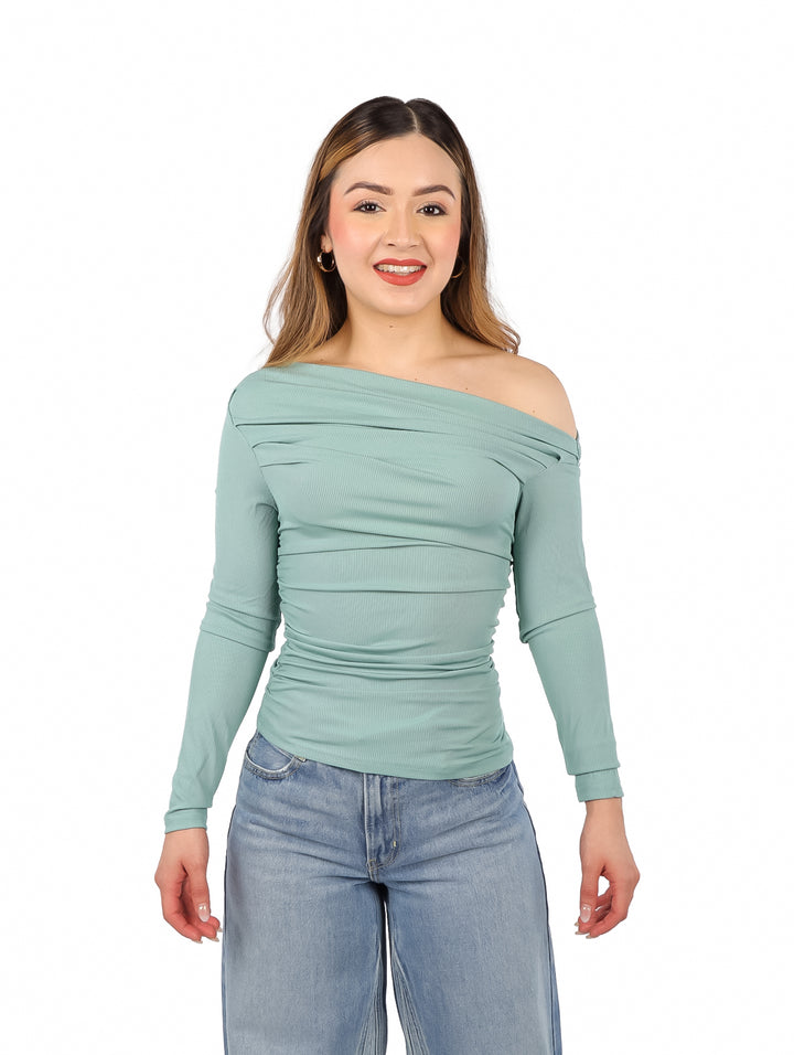 Mujer vistiendo blusa color jade de un solo hombro y pantalones azules.