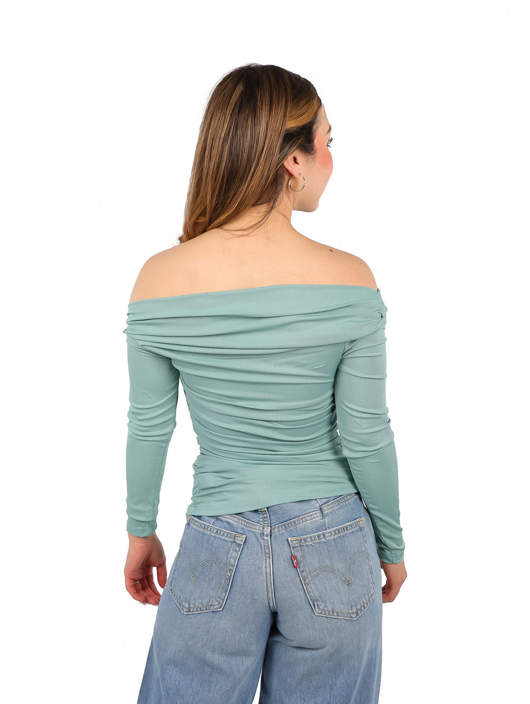 Mujer vistiendo blusa color jade de un solo hombro y pantalones azules.