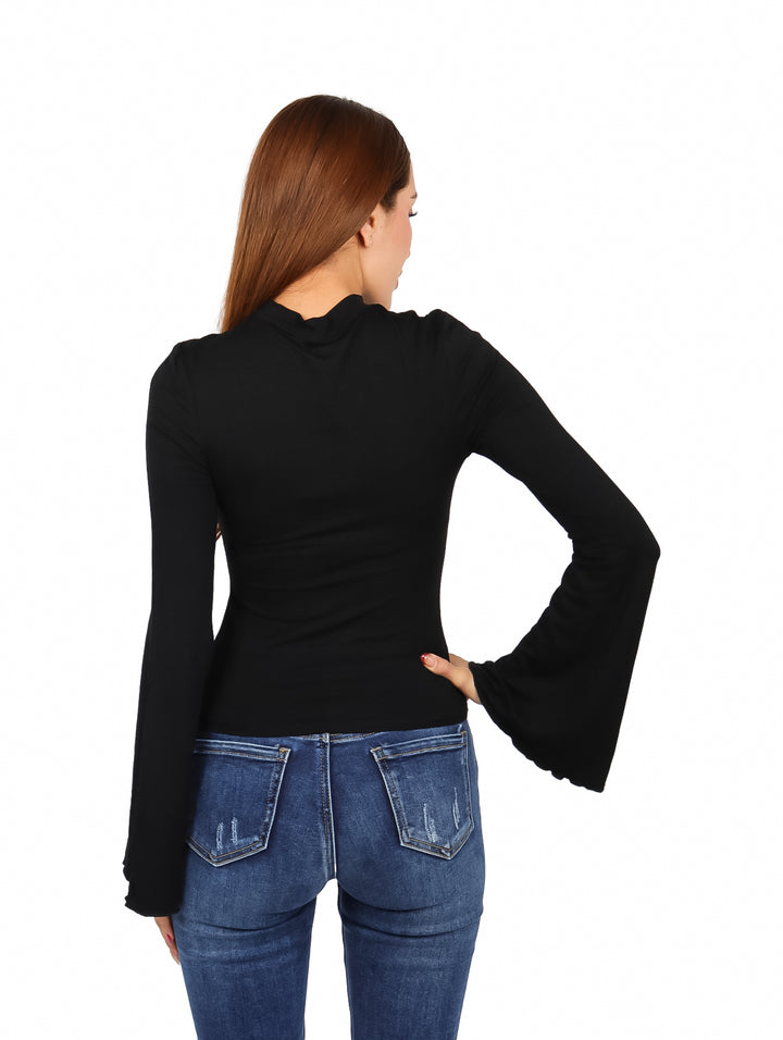 Mujer modelando blusa negra de manga campana y cuello alto con pantalones de mezclilla azules.