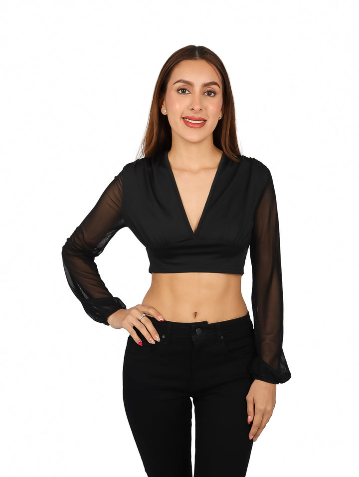 Mujer vistiendo blusa negra crop top con escote en V y mangas largas transparentes.