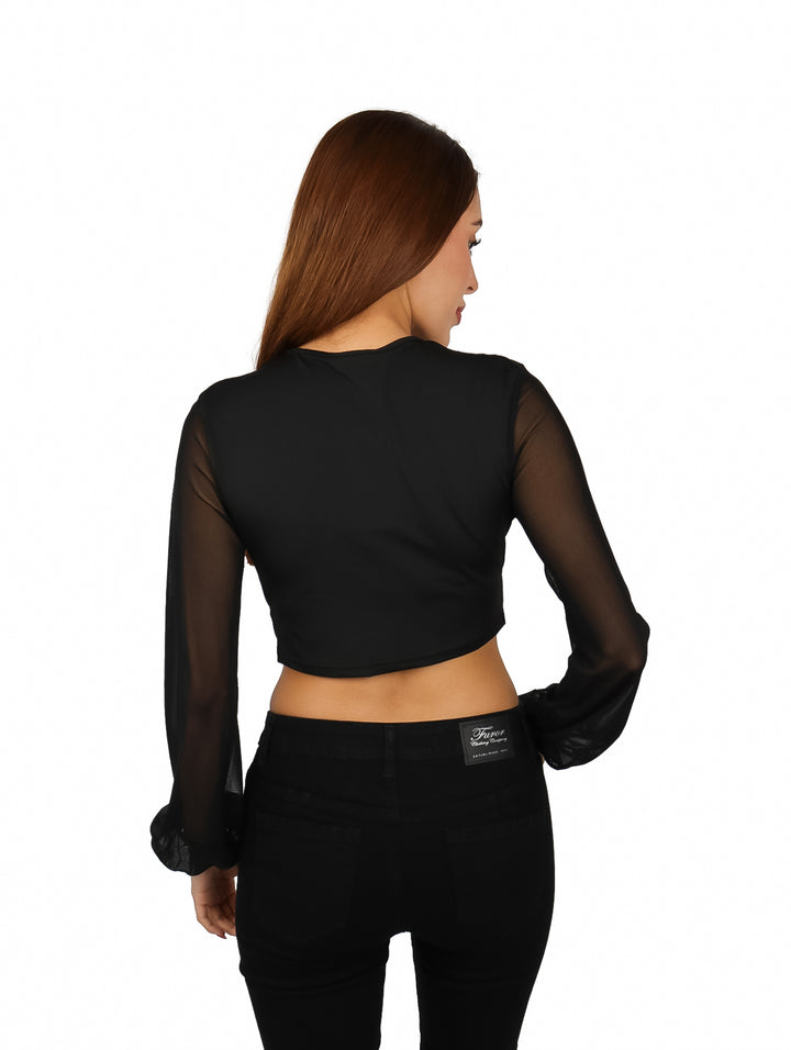 Mujer vistiendo blusa negra crop top con escote en V y mangas largas transparentes.