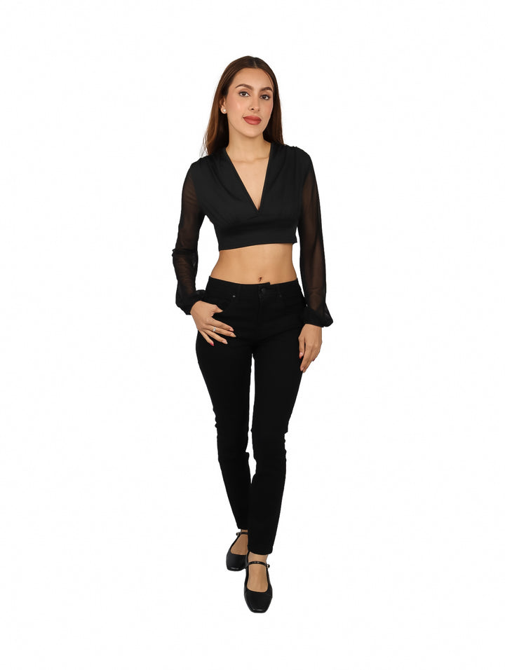 Mujer vistiendo blusa negra crop top con escote en V y mangas largas transparentes.