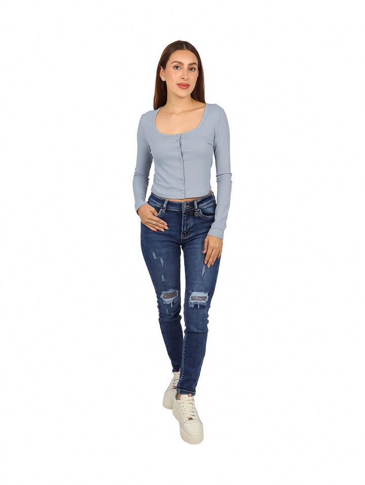 Mujer vistiendo blusa corta azul claro con botones frontales y manga larga.
