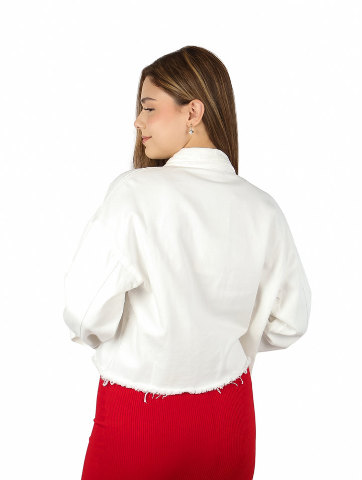 Mujer vistiendo una chamarra corta de mezclilla blanca sobre un vestido rojo.