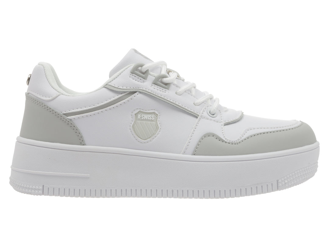 Tenis K-Swiss blancos con detalles en gris y suela de plataforma blanca.