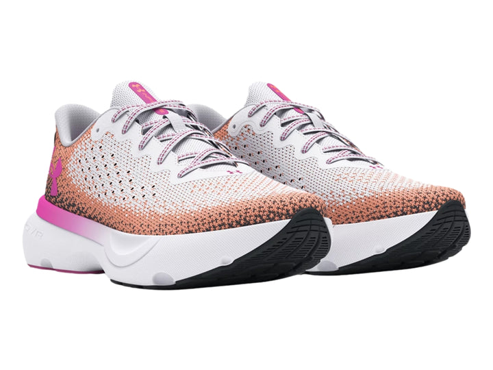 Tenis deportivos Under Armour blancos con degradado en rosa y naranja y suela blanca.