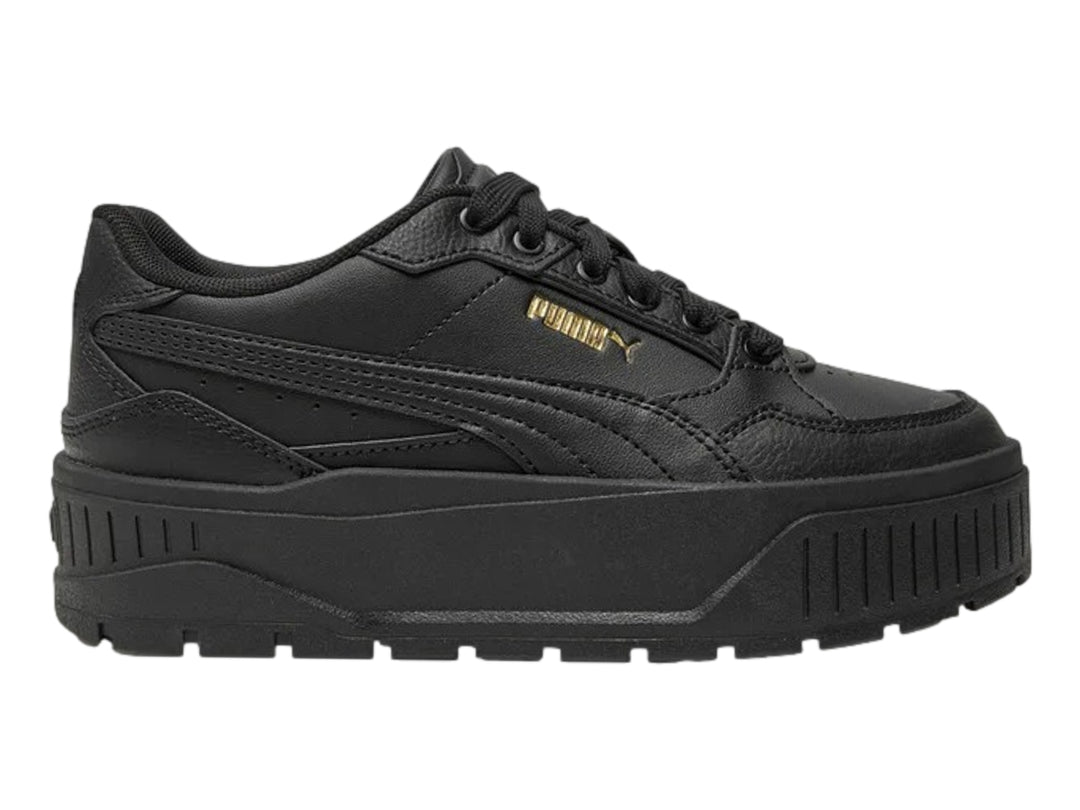 Tenis PUMA color negro con suela de plataforma gruesa y logotipo dorado en el lateral.