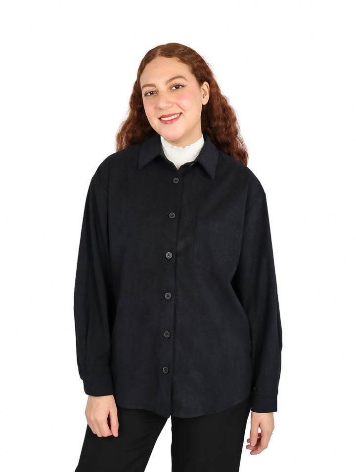 Mujer vistiendo una camisa de pana color negro de manga larga con botones frontales.