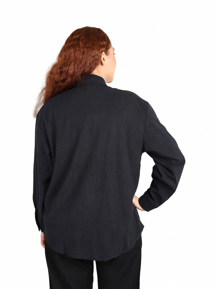 Mujer vistiendo una camisa de pana color negro de manga larga con botones frontales.