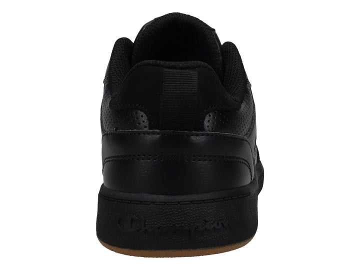 Tenis Champion color negro con suela de goma marrón, diseño deportivo de corte bajo.