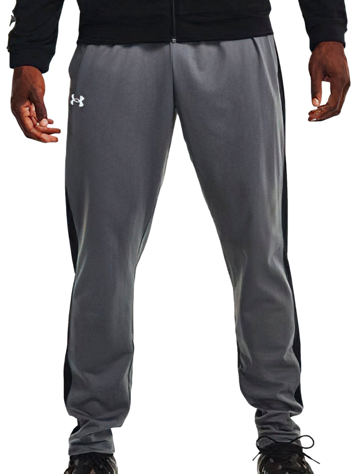 Pantalones deportivos Under Armour en color gris con franjas negras laterales y logotipo blanco.