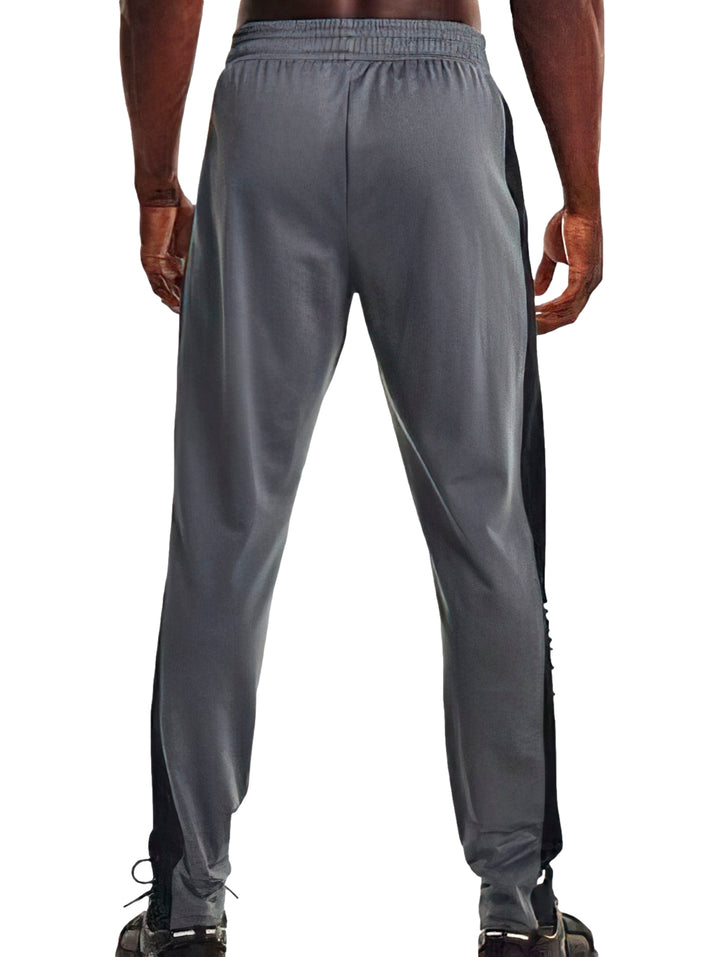 Pantalones deportivos Under Armour en color gris con franjas negras laterales y logotipo blanco.