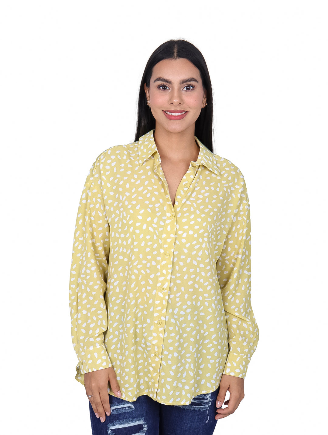 Mujer vistiendo una camisa de manga larga color lima con estampado de pequeños óvalos blancos.