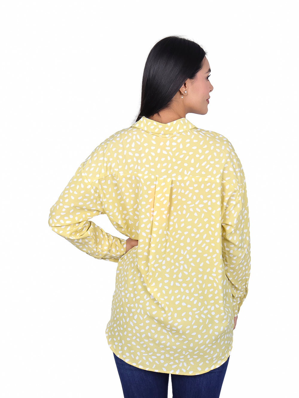 Mujer vistiendo una camisa de manga larga color lima con estampado de pequeños óvalos blancos.