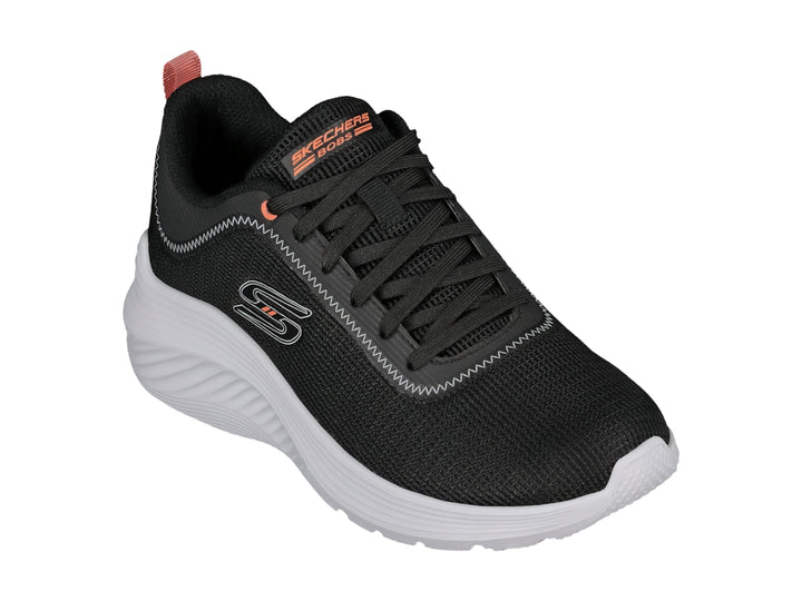Tenis deportivos Skechers color negro con suela blanca y detalle naranja en el talón.